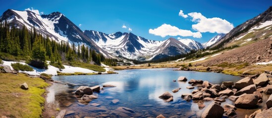 Wall Mural - A mountain lake sits nestled among snow-covered peaks atop Independence Pass. The serene lake reflects the rugged beauty of the surrounding mountains, creating a stunning winter scene.