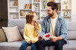 © Maria Vitkovska - Smiling father holding a card from his little daughter, both sitting on sofa, looking at each other
