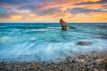 Landscape of rocky beach at sunset with ocean waves and pebbles on Co Thach beach, a famous beach in Binh Thuan province, central Vietnam