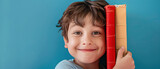 Fototapeta Zwierzęta - happy boy next to some books on a blue background