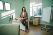 © Айман Дайрабаева - Happy young Businesswoman in Office. Stylish Beautiful Manager Smiling leans on the work table