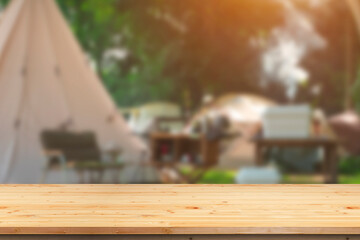Wall Mural - empty wooden table top on blurred background of camping tents in campground area at nature parkland 