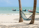 Fototapeta Kosmos - Hammock under coconut palm trees at sandy beach on sunny day, travel summer holidays concept