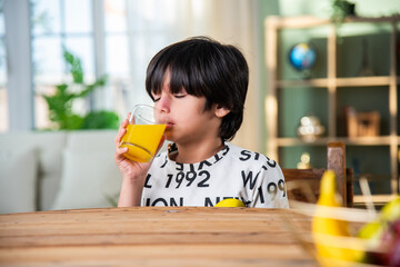 Indian boy drinking fresh juice in a glass at home