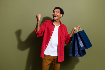 Wall Mural - Photo of positive lucky man dressed red shirt rising shoppers looking empty space isolated green color background