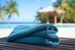 © Noble Nature - drap de plage, serviette bleue sur une plage de sable dans un lieu paradisiaque vu de manière flouté en arrière-plan. Vacances à la mer, exotisme, réservation, agence de voyage, départ, congé.