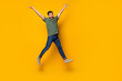 Full size photo of handsome young guy jump raise hands dressed stylish khaki outfit isolated on yellow color background