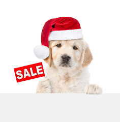 Wall Mural - Cute Golden retriever puppy wearing santa hat shows signboard with labeled 