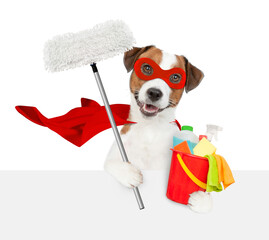 Poster - Happy Mastiff puppy wearing superhero costume holds the mop and bucket with washing fluids above empty white banner. Isolated on white background