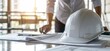 © kitti - Engineer Safety White Helmet on Work Table and Blueprint for Planing Project