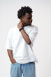© fotofabrika - Portrait of a smiling young african man wearing white t-shirt standing over gray background