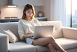 © anmitsu - Beautiful young Asian female freelancer is sitting on a comfortable sofa and browsing the internet on a laptop to successfully conduct business. Luxurious interior. Work from home concept.