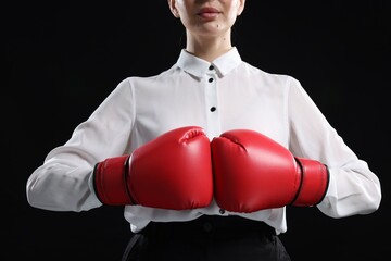 Sticker - Businesswoman in shirt wearing boxing gloves on black background, closeup