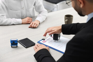 Wall Mural - Immigration to United Kingdom. Embassy worker approving visa application form to woman in office, closeup