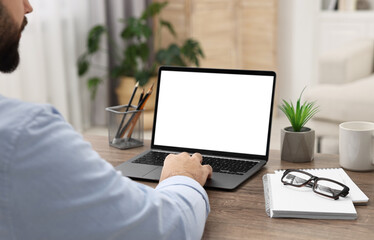 Poster - E-learning. Young man using laptop at wooden table indoors, closeup