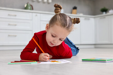 Wall Mural - Cute little girl coloring on warm floor in kitchen. Heating system