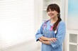 © New Africa - Mammologist with pink ribbon in hospital, space for text. Breast cancer awareness