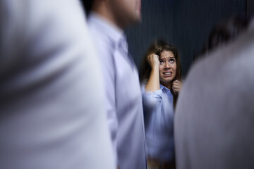 Woman, people and trapped with social anxiety at work with stress, scared and overthinking with concern. Female person, coworkers and crowd with worry for deadline at office and stuck at office