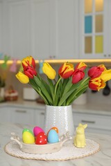 Sticker - Easter decorations. Bouquet of tulips, painted eggs and bunny figure on table indoors