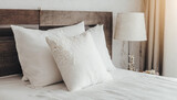 Fototapeta  - Clean Bedding sheets and pillow on natural wall room background. White bedding and pillow in hotel room. White pillows on empty bed.