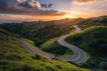 Wall Mural - A winding road in a mountainous landscape during sunset.