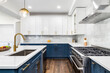 © Joseph Hendrickson - A luxurious white and blue kitchen with gold hardware, stainless steel appliances, and white marbled granite countertops. No brands or labels.
