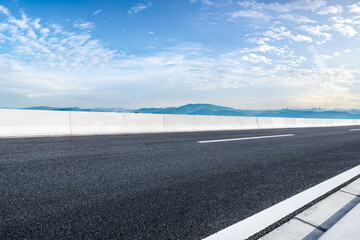 Wall Mural - Empty asphalt road and mountains with city skyline