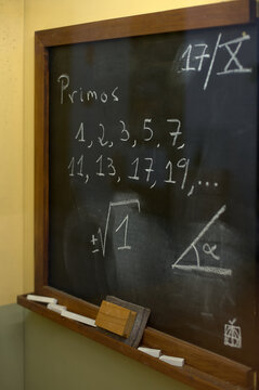 Classroom blackboard showing a list of prime numbers and geometric drawings, ideal for educational contexts.