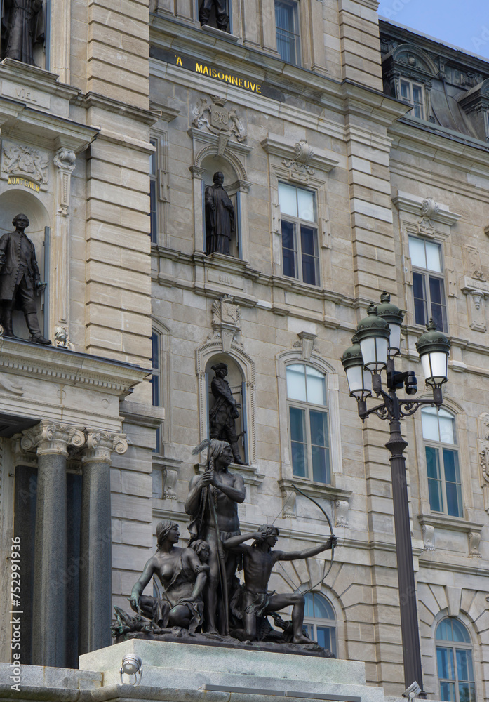 10.06.2023, Quebec, Canada. Quebec Parliament building architecture with sculptures and flag of Quebec. Clock tower of the Quebec parliament building and the statues of the indigenous people. 