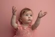 Against a solid blush pink background, the most endearing little baby reaches out with tiny hands, spreading love and warmth to all.