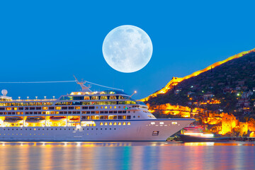 Wall Mural - Beautiful white giant luxury cruise ship on stay at Alanya harbor with full moon - Alanya, Turkey 