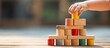 © HN Works - Child's Hand Engaging in Interactive Play by Adding Colorful Block to Tower