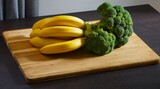 Fototapeta Fototapety do kuchni - Dojrzałe banany i brokuł gotowy do pokrojenia. Świeże owoce i warzywa na stolnicy. Stół, deska do krojenia, banany i brokuł