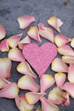 Fototapeta Zwierzęta - pink and light flowers on concrete background as voucher or card background with pink chocolate heart with sugar pearls