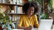 © buraratn - Happy young woman using laptop sitting at desk writing notes while watching webinar, studying online