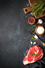 Canvas Print - Raw meat steak with spices on black background. Beef steak ribeye. Top view with copy space.