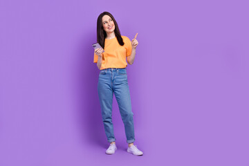 Wall Mural - Full body length photo of business woman pointing empty space actual trends in tik tok using smartphone isolated on purple color background