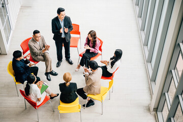 Wall Mural - Top view captures a diverse group in a busy office, collaborating and engaged in discussions. A businessman and businesswoman sit at a conference, allowing for your business meeting concept.