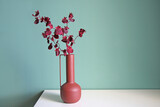 Fototapeta Tulipany - Blooming branch in a modern ceramic vase on a white table. Space for your text.