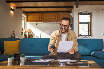 one adult man sit at home make a call while hold paper documents