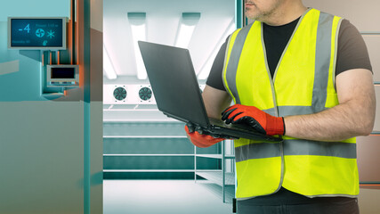 Wall Mural - Worker near industrial refrigerator. Entrance to freezer. Cropped man with laptop in hands. Engineer sets up refrigeration equipment. Industrial refrigerator for pharmaceutical factory.