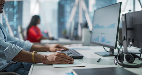 Close Up of a Young Indian Male Professional Working in a Business Research and Development Company. Handsome Manager Analyzing Financial Reports, Looking at a Computer Screen with Graphs and Charts