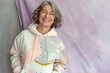 © Oksana Smyshliaeva - A beaming senior woman sports a trendy pastel hoodie, her laughter a bright note against a soft lilac backdrop, showcasing a whimsical kidcore vibe..