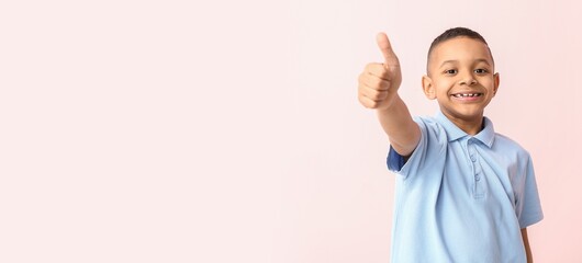 Wall Mural - Smiling African-American boy showing thumb-up on light pink background with space for text