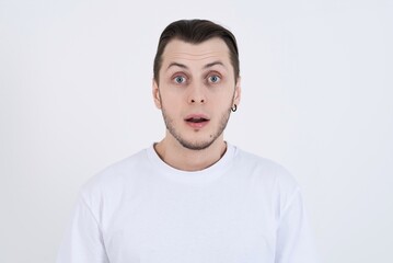 Wall Mural - Portrait of shocked attractive caucasian young man in casual clothes with open mouth isolated on white studio background