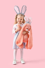 Wall Mural - Cute little girl with bunny ears and plush toy on pink background. Easter celebration