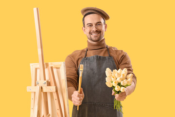 Poster - Happy male artist with easel and bouquet of tulips on yellow background. International Women's Day