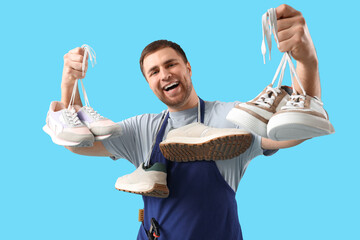 Wall Mural - Male shoemaker with tools and sneakers on blue background