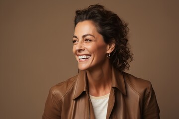 Beautiful smiling middle aged woman in brown jacket on brown background.