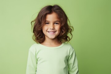 Wall Mural - Portrait of a cute little girl with long curly hair over green background